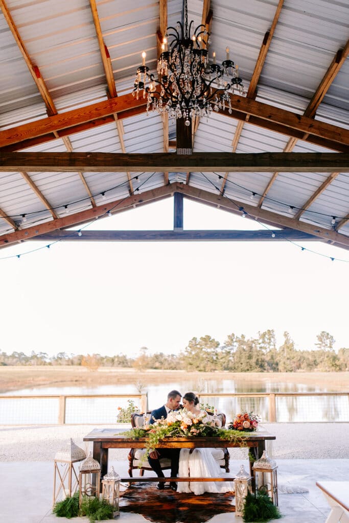 man and woman seated at sweatheart table during wedding reception for a barn style wedding